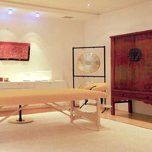 Abbildung: Massageliege mit chinesischen Gong und antiken Chinesischen -Hochzeitsschrank